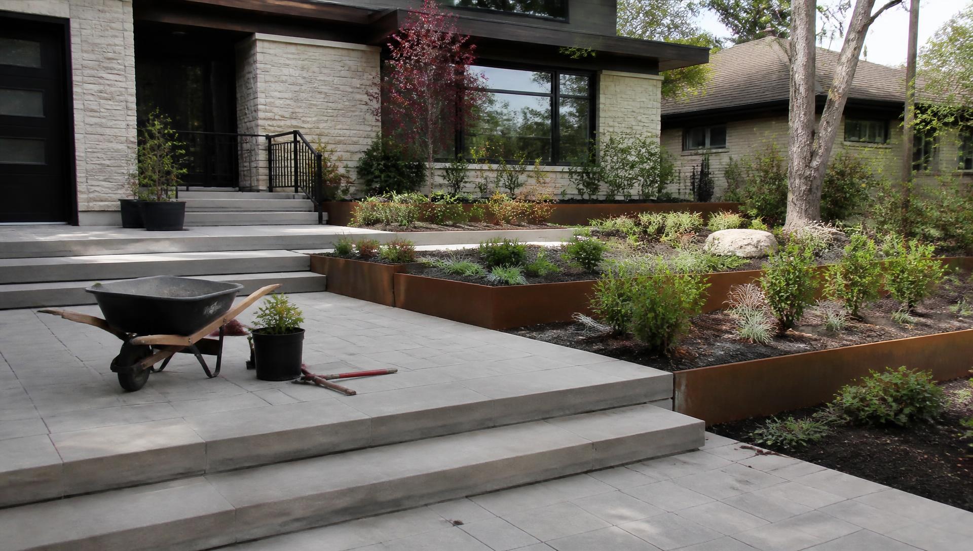 Front yard construction staging with finished paving corten steel planters and newly planted shrubs. Images Created by www.TinyHome-Revolution.com